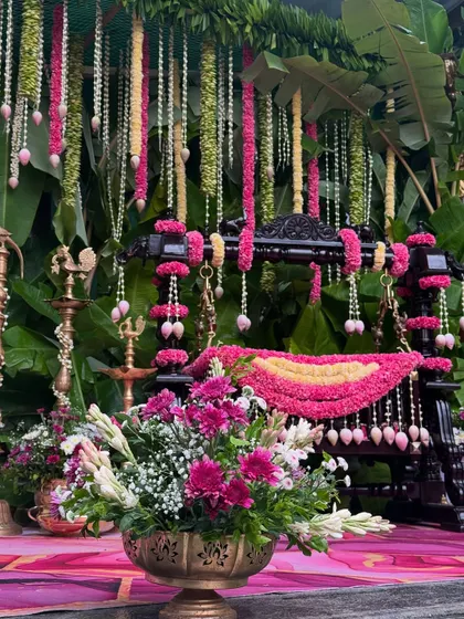 A detailed shot of the naming ceremony cradle, beautifully decorated with pink flowers and traditional lotus bud hangings.