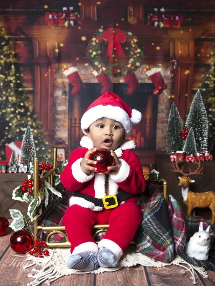Another adorable shot of the little Santa, capturing his surprised expression as he holds a Christmas bauble.