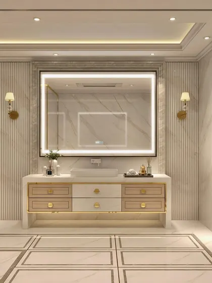 This luxurious bathroom is designed with a palette of cream, taupe, and gold. The space is minimal yet opulent, featuring a large backlit mirror, marble walls, and refined gold fixtures.