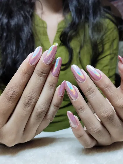 Make a statement with these stunning holographic chrome nails. The light-reflecting powder creates a mesmerizing effect on these long, almond-shaped extensions, shifting colors with every movement.