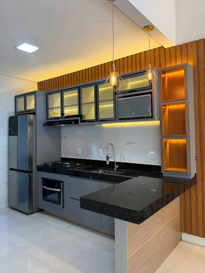 A stunning grey kitchen with a breakfast bar extension. The design features wood paneling and integrated lighting, creating a warm and inviting focal point in this open-plan space.