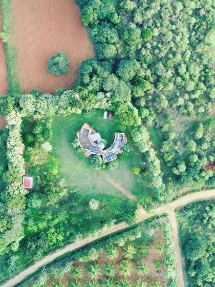 This is another beautiful aerial view showing the farmhouse and its relationship to the wider agricultural landscape. The design intentionally preserves a large expanse of lawn and green space, connecting the home to its rural context and providing ample room for outdoor activities.