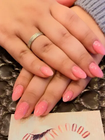 A soft and pretty set of almond-shaped nails in a shimmery, light pink color. This is a delicate and feminine choice for any occasion.