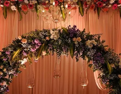 A close-up of the floral arch from a classic reception stage. I used a mix of fresh flowers and hanging glass candle holders to add detail and warmth to the design.
