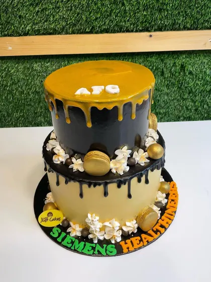 A 4kg two-tiered corporate cake with black and gold drip effects, decorated with golden macarons.