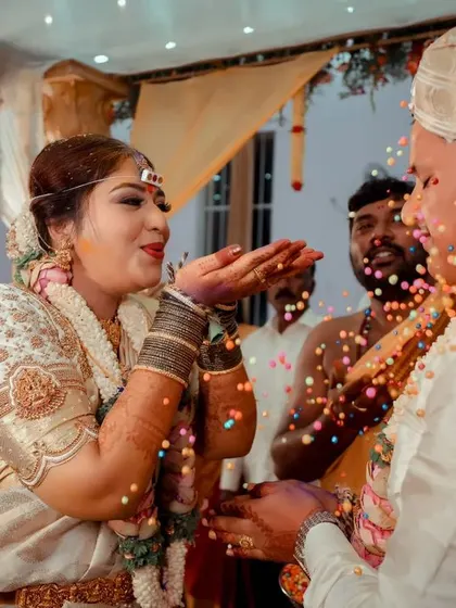 A playful moment during the wedding ceremony as the bride blows a handful of celebratory rice towards the groom.