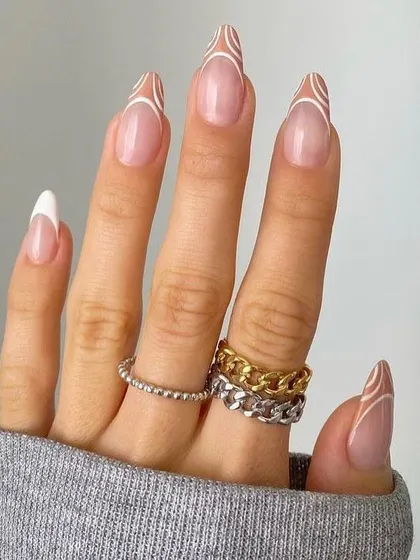 An intricate and delicate design featuring fine white lines that create a swirling, abstract pattern over a classic white French tip. This is a beautiful example of detailed line work on long almond nails.