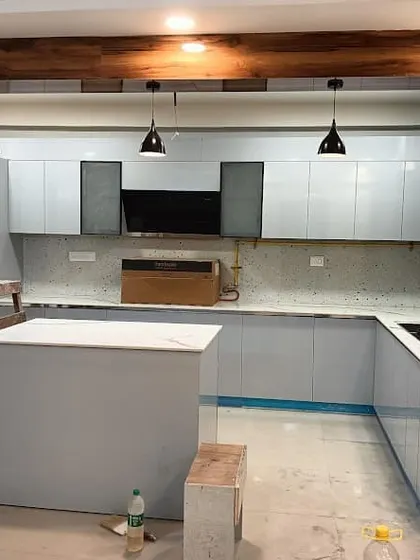 A behind-the-scenes look at a U-shaped kitchen installation in progress. This design includes an island for extra prep space and sleek, light grey cabinetry.