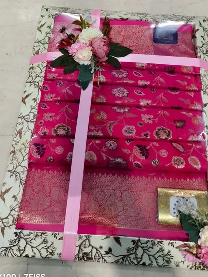 Another example of a large tray packed with bright pink sarees for a wedding.