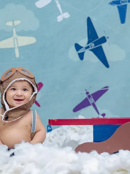 A happy little pilot flashes a big smile for the camera, showcasing the fun and imaginative 'Aviator' theme available for sitter sessions.