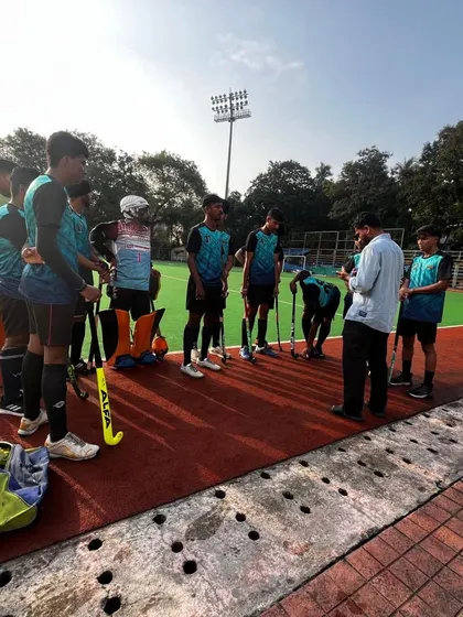 Our coach gives a pre-game briefing to the team at the B.K. Mohite Memorial Hockey Tournament. Strategy and motivation are key components of our competitive success.