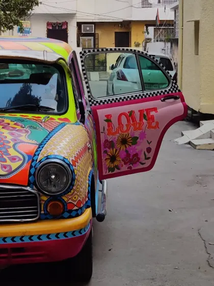 A close-up of the painted Ambassador car's door, featuring the word "LOVE" amidst floral patterns. Every inch of the car was covered in unique designs.