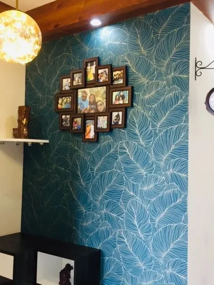 This teal wallpaper with a white feather pattern is a popular choice for creating a stylish and modern accent wall. Here, it provides a beautiful backdrop for a family photo collage.