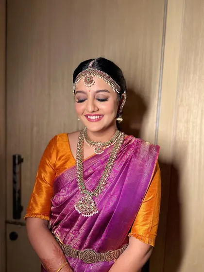 A lovely South Indian bridal hairstyle featuring a bubble braid adorned with fresh flowers and traditional temple jewellery. This is a modern interpretation of a classic look.