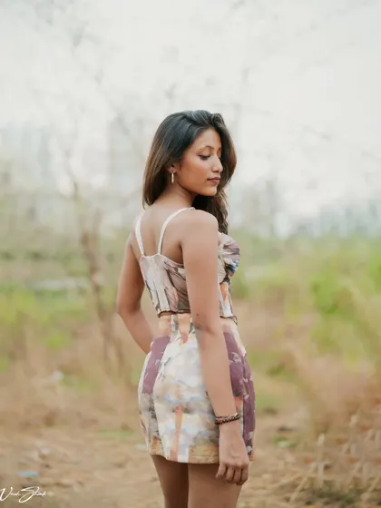 A three-quarter portrait with a soft, contemplative expression. The focus here is on the model's profile and the texture of the clothing against the natural, muted tones of the background.