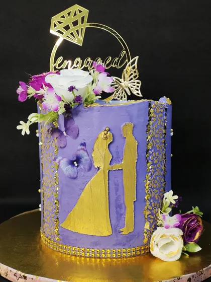 I designed this purple and gold cake for an engagement party. A silhouette of the couple is the centerpiece, surrounded by delicate buttercream stenciling, butterflies, and fresh flowers for a romantic and personalized touch.