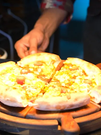 A freshly baked pizza being served at our live Pizzeria station. The sight of a hot, delicious pizza straight from the oven is always a crowd-pleaser at corporate events.