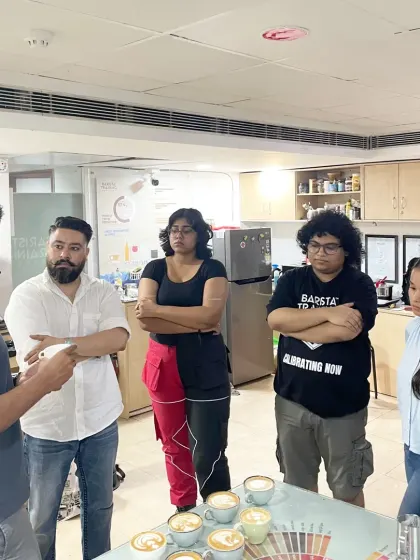 A group of students listening intently as Adwaith Menon critiques their latte art. Peer learning and expert feedback are central to our workshops.