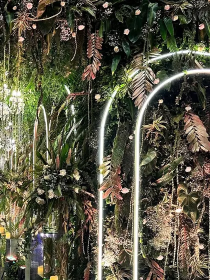 Another angle of the lush green wall, showing the interplay of neon lights, diverse foliage, and sparkling details that create an enchanted forest feel.