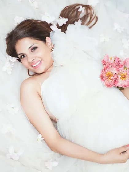 A dreamy, ethereal portrait from above, with the mother-to-be lying in a sea of soft tulle and delicate flowers. This style creates a truly angelic and serene image, focusing on peaceful anticipation.