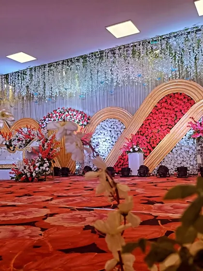 A closer look at a grand reception stage with a unique scalloped backdrop of red and white flowers.