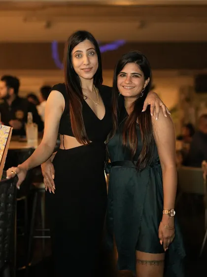 Two friends posing for a picture, dressed in classic black for a night out.