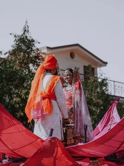 The couple sharing a look during their grand Varmala ceremony, standing on a large, decorative lotus structure.