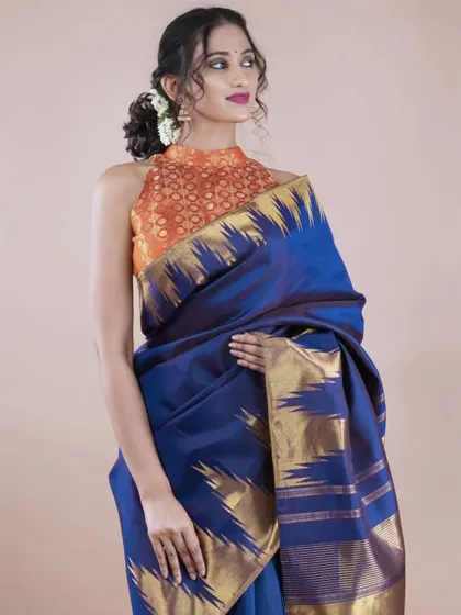 Here you can see how a traditional Kanjivaram silk saree can be styled for a contemporary look. The rich blue silk is paired with a modern halter-neck brocade blouse, creating a perfect fusion of classic and chic.