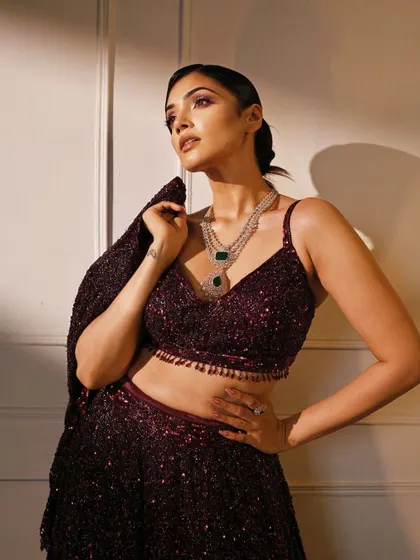 A confident pose in a stunning sequined lehenga. The jacket-style dupatta adds a layer of modern sophistication to the outfit.