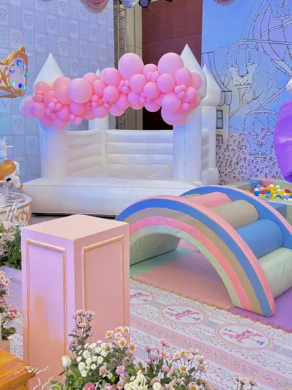 The dedicated soft play area, featuring a white bouncy castle, a pastel rainbow climber, and a ball pit, all thematically colored to blend seamlessly with the elegant party decor.