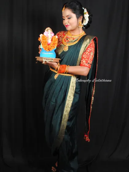 A festive Marathi look for Ganesh Chaturthi. The model is holding a Ganesha idol, and her makeup and attire reflect the celebratory spirit of the festival.