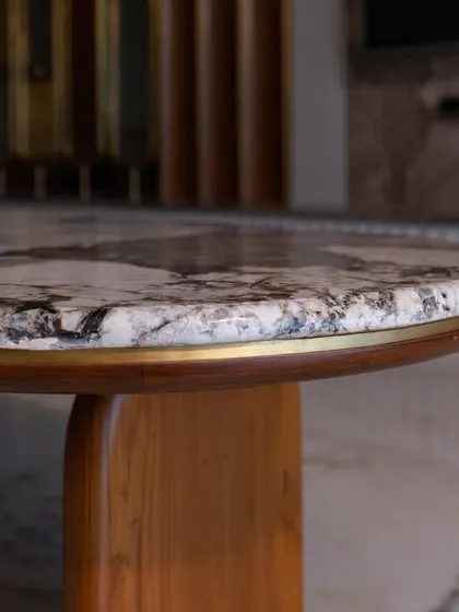 A close-up of the coffee table's edge, showing the beautiful grain of the wood and the brass inlay bordering the marble.