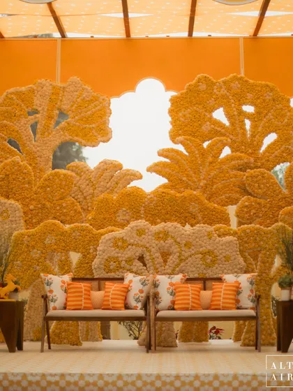 The main seating area at the 'Kesar Sehar' Haldi, with a backdrop made entirely of marigolds depicting a forest scene. This was an immersive cultural experience for the guests.