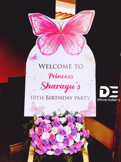 A personalized welcome sign for a princess's 10th birthday party, featuring a large pink butterfly and a beautiful floral arrangement at the base.