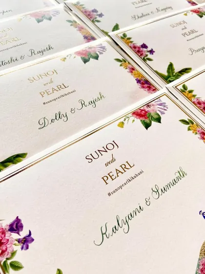 A detail shot of the personalized place cards, showing the elegant calligraphy and the vibrant floral watercolor design. These small touches make each guest feel personally welcomed.