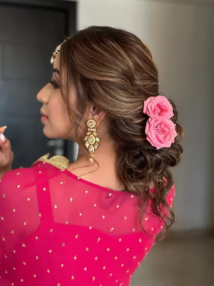A low, soft, textured bun decorated with fresh roses. This romantic updo is perfect for a wedding guest, using extensions to create a fuller bun that holds the flowers perfectly.