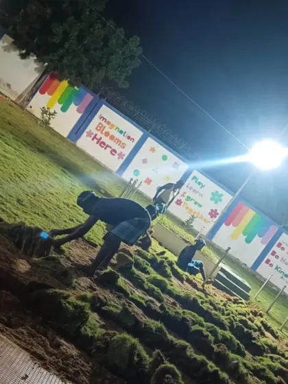 Laying the final sections of the lawn. You can see the new green space taking shape against the colorful wall of the kindergarten.