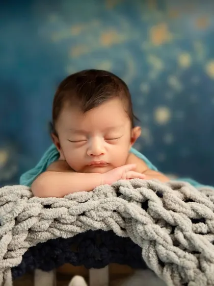 Another beautiful close-up from the dreamy star-themed session. The baby's hands are gently tucked under his chin, showing his tiny, delicate fingers.