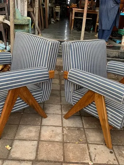 A pair of iconic "Kangaroo" chairs, a low-slung design by Pierre Jeanneret. I recreated these with a solid teak frame and comfortable, striped upholstery with bolster armrests.