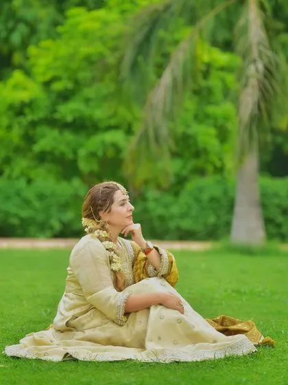 A thoughtful, candid moment captured on the grass. This relaxed pose in a full lehenga shows that traditional wear can be comfortable and natural, not just for formal occasions.