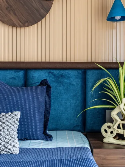 A close-up of the bedside in the blue-themed room, highlighting the playful bicycle-shaped planter and the texture of the headboard and wall paneling.