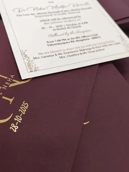 This shot reveals the invitation insert with its delicate gold border, contrasting beautifully with the deep portwine envelope.