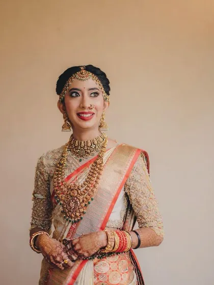 This bride looks poised and elegant in her off-white Kanchivaram saree. The custom-designed blouse adds a touch of sophistication to her look.