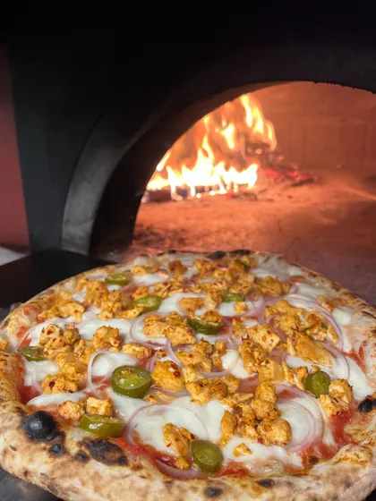 Our Polo pizza with chicken and jalapeños, glowing in front of the fire.