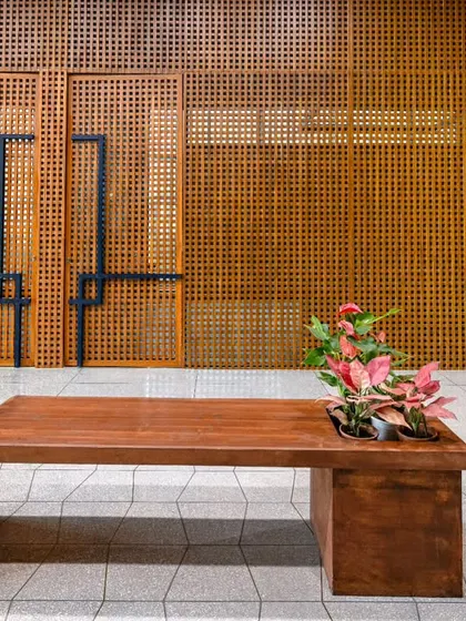 The lift lobby at Anthea Pharma, showcasing wooden blockwork finished in teak. The main entry door is highlighted in dark blue, with matching handles on the conference room doors for a cohesive design.