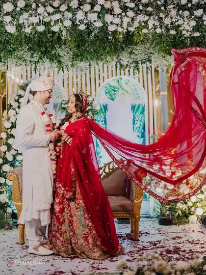 A beautiful shot of the couple during their Varmala, with the bride's red veil flowing in the air.