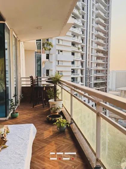 A beautiful city view from a well-appointed balcony at sunset. The space is simply decorated with potted plants and a small seating area to maximize the sense of openness.