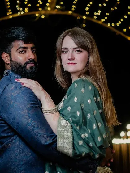 A stylish portrait of the couple posing under a lit archway at their reception.