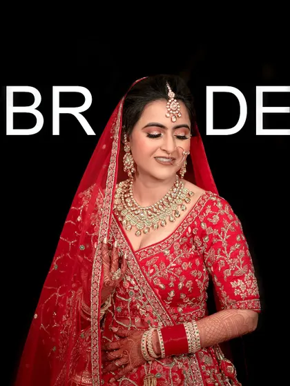 A classic portrait of the bride in her red lehenga, looking happy and radiant on her wedding day.