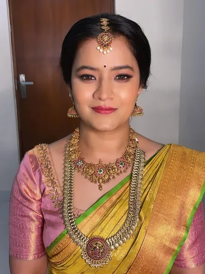 This bride's makeup features a soft smokey eye and a neutral pink lip, a beautiful combination that works perfectly with her yellow and pink silk saree.